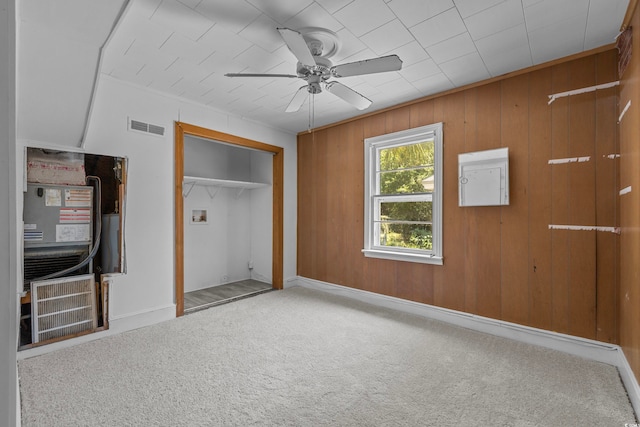 unfurnished bedroom featuring wood walls, carpet, and ceiling fan