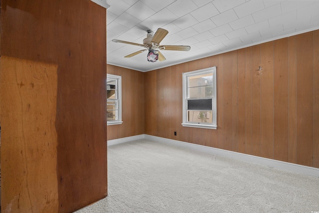 spare room with ceiling fan, a healthy amount of sunlight, carpet floors, and wood walls