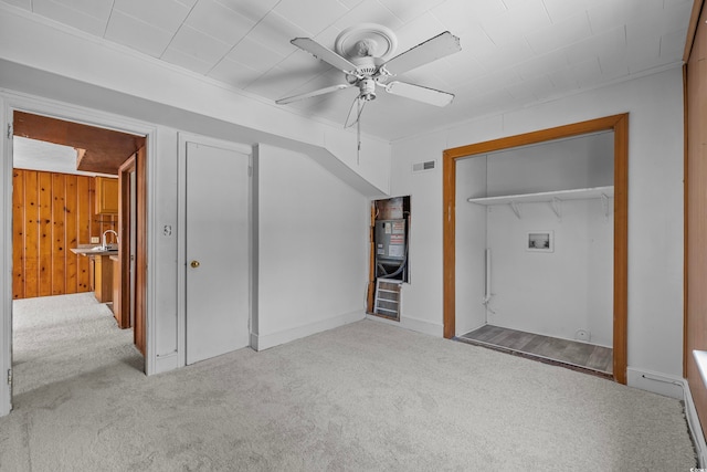 unfurnished bedroom featuring wood walls, light carpet, a closet, and ceiling fan