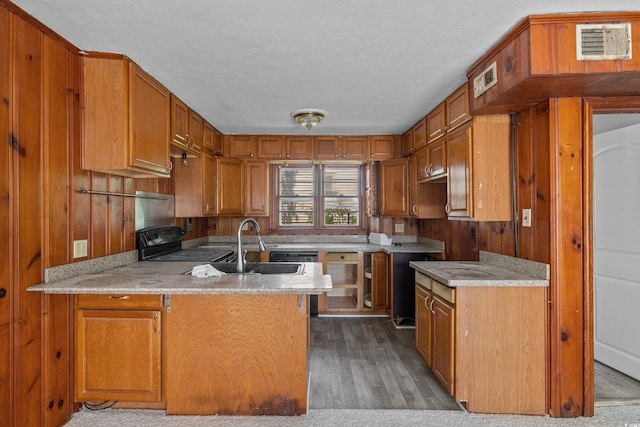 kitchen featuring kitchen peninsula, hardwood / wood-style floors, a textured ceiling, and black range oven