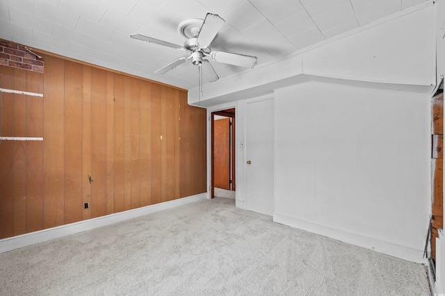 carpeted spare room featuring ceiling fan and wood walls