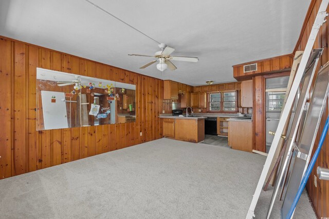 kitchen featuring black dishwasher, light carpet, kitchen peninsula, and wood walls