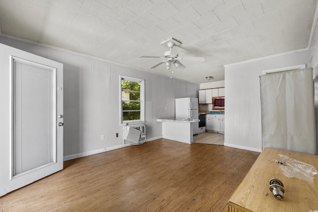 unfurnished living room featuring ceiling fan, an AC wall unit, ornamental molding, and light hardwood / wood-style flooring