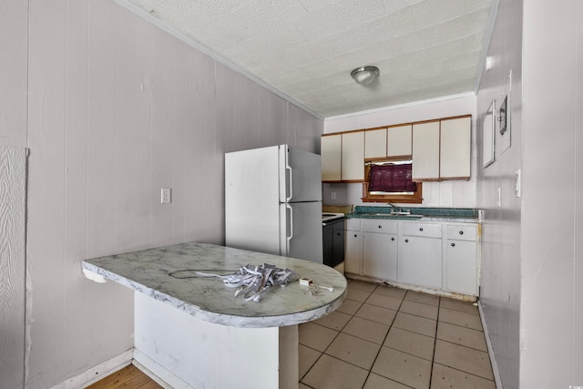 kitchen featuring light tile patterned flooring, sink, kitchen peninsula, white cabinetry, and white fridge