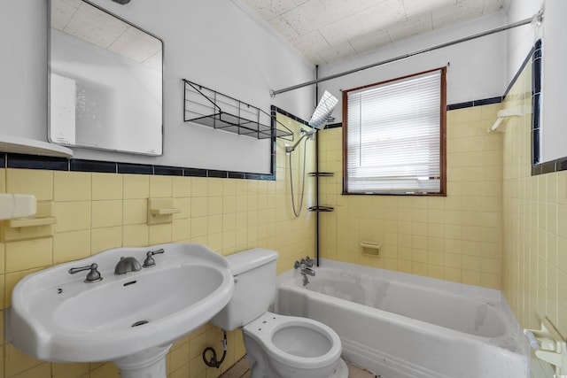 full bathroom featuring toilet, tiled shower / bath, sink, and tile walls