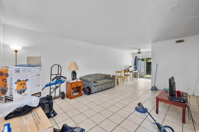 tiled living room featuring ceiling fan and a textured ceiling