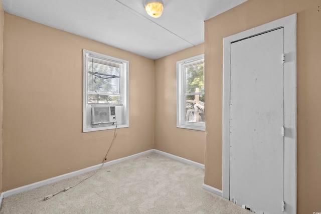 unfurnished room featuring cooling unit and light colored carpet