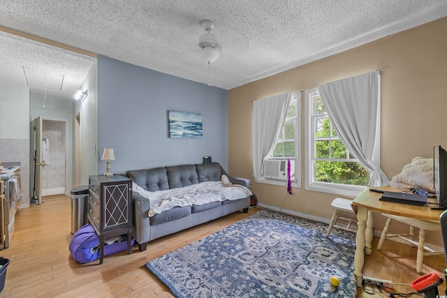 living room featuring cooling unit, a textured ceiling, wood-type flooring, and ceiling fan