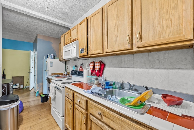 kitchen featuring tile countertops, a textured ceiling, light hardwood / wood-style floors, and white appliances