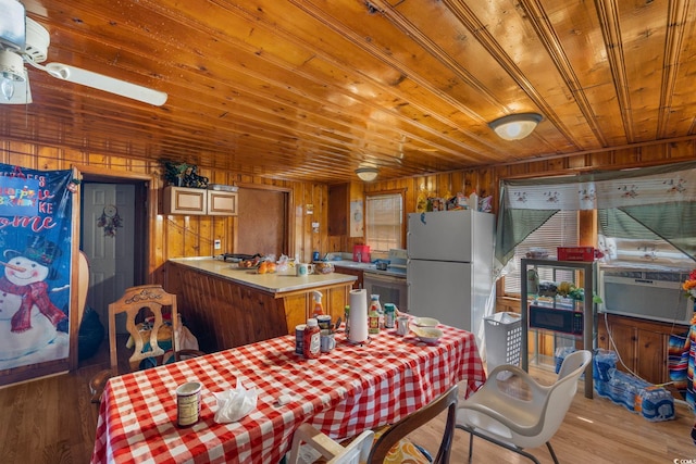 kitchen with white refrigerator, wood walls, hardwood / wood-style floors, and a kitchen island