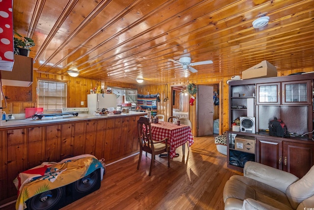 kitchen featuring wooden walls, ceiling fan, hardwood / wood-style flooring, kitchen peninsula, and white fridge