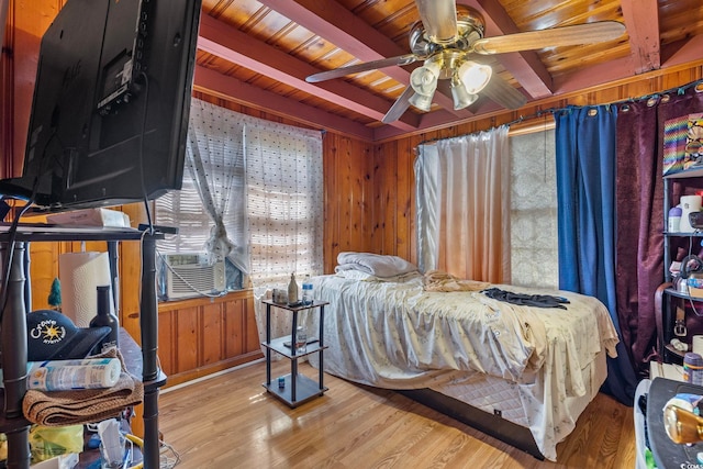 bedroom featuring ceiling fan, beamed ceiling, and wooden walls