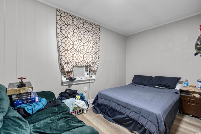 bedroom featuring crown molding, cooling unit, wood walls, and light hardwood / wood-style flooring