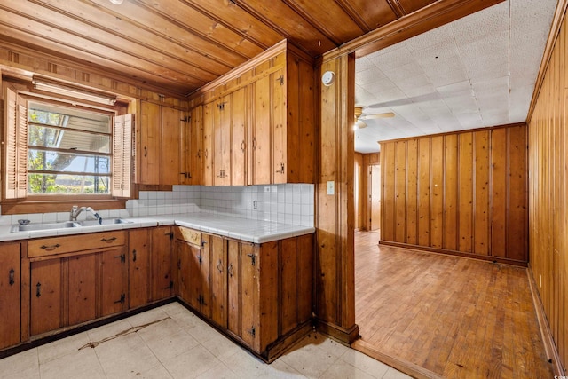 kitchen featuring ceiling fan, wood walls, sink, light hardwood / wood-style floors, and decorative backsplash