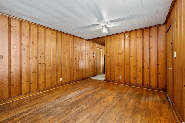 spare room featuring wooden walls, ceiling fan, and wood-type flooring