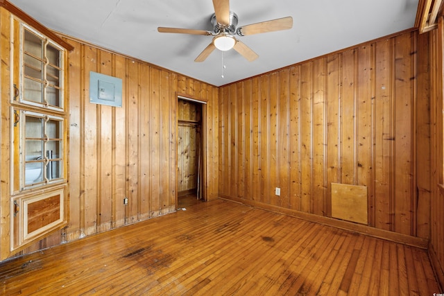 spare room featuring ceiling fan, hardwood / wood-style flooring, and wooden walls