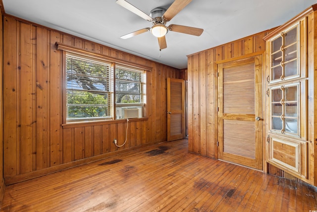 unfurnished room with ceiling fan, cooling unit, dark hardwood / wood-style floors, and wood walls