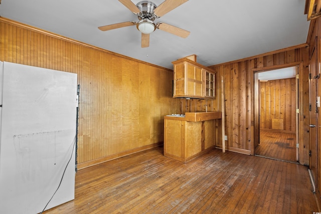 kitchen with white fridge, ceiling fan, wood walls, and hardwood / wood-style floors