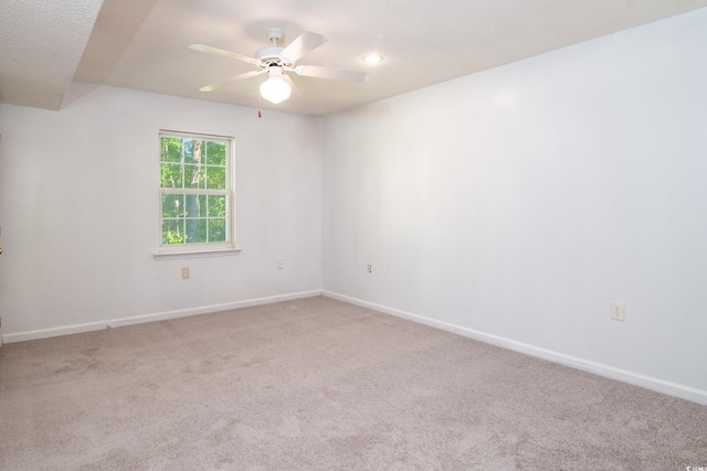 spare room featuring light carpet, ceiling fan, and a textured ceiling