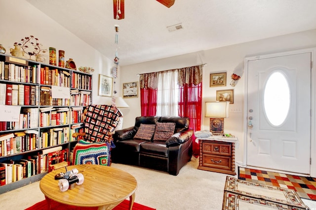 interior space with a textured ceiling, lofted ceiling, ceiling fan, and light carpet