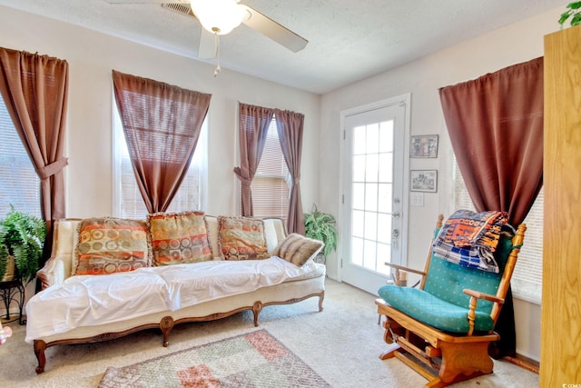 living room featuring a textured ceiling, a healthy amount of sunlight, light carpet, and ceiling fan