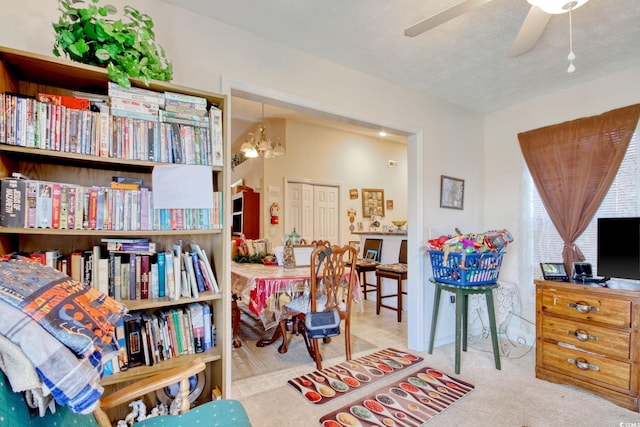 sitting room with light carpet, a textured ceiling, and ceiling fan with notable chandelier