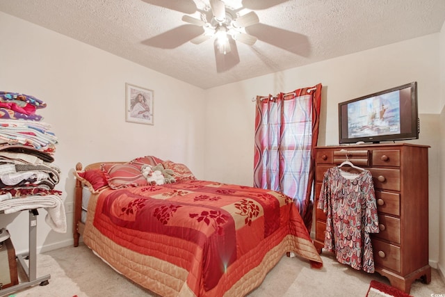 bedroom featuring ceiling fan, a textured ceiling, and light carpet