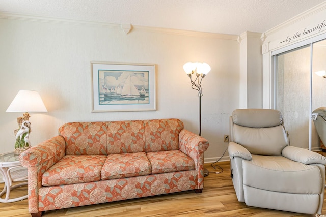 living room with ornamental molding, light wood-type flooring, and a textured ceiling