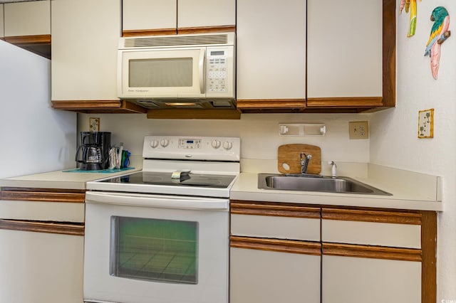 kitchen with white appliances, sink, and white cabinetry