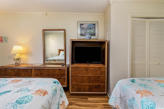 bedroom featuring ornamental molding, a closet, wood-type flooring, and a textured ceiling