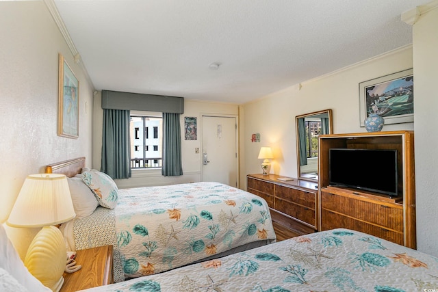 bedroom with a textured ceiling, hardwood / wood-style floors, and ornamental molding