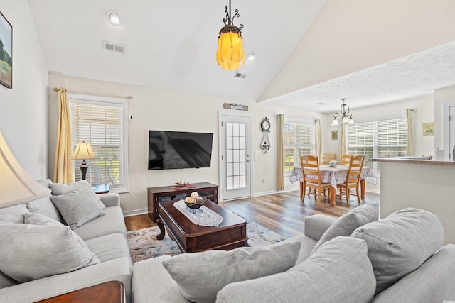 living room featuring hardwood / wood-style flooring, a notable chandelier, and high vaulted ceiling