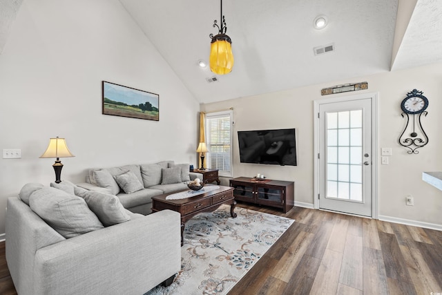 living room with dark wood-type flooring, high vaulted ceiling, and a healthy amount of sunlight