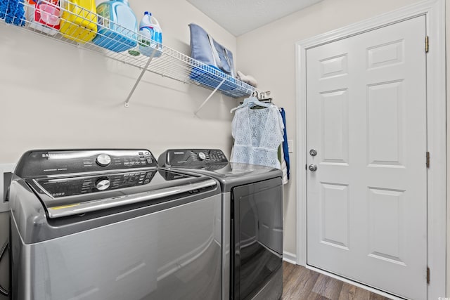 clothes washing area featuring separate washer and dryer, a textured ceiling, and dark wood-type flooring