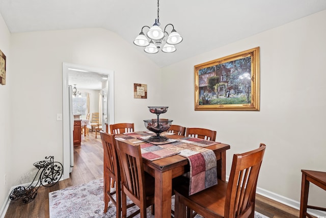 dining room with wood-type flooring, a chandelier, and vaulted ceiling