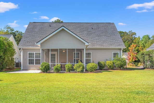 rear view of property with cooling unit, a sunroom, and a yard