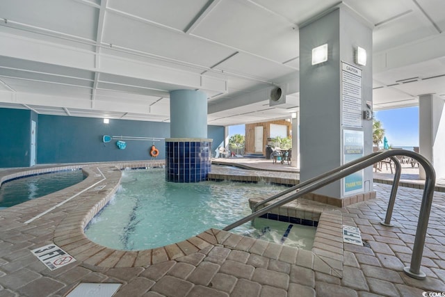 view of swimming pool featuring pool water feature and an indoor hot tub