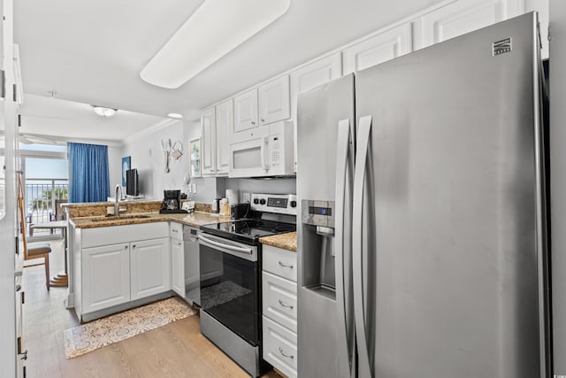 kitchen featuring kitchen peninsula, white cabinets, appliances with stainless steel finishes, light wood-type flooring, and sink