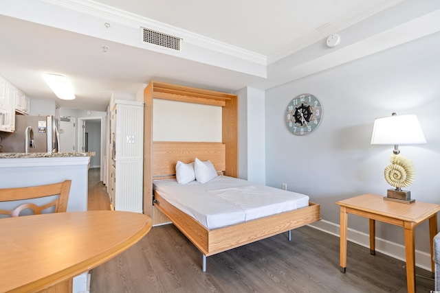 bedroom with crown molding, stainless steel refrigerator with ice dispenser, and dark hardwood / wood-style flooring