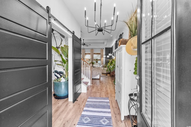 entryway featuring a chandelier, a barn door, and light hardwood / wood-style floors