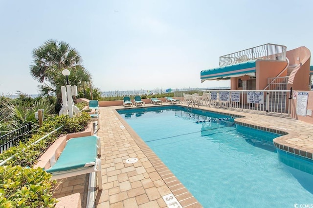 pool with a patio area and fence