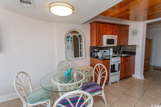 kitchen with visible vents, dark countertops, tasteful backsplash, light tile patterned floors, and white appliances