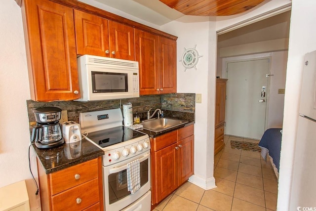 kitchen with a sink, white appliances, brown cabinetry, decorative backsplash, and light tile patterned floors