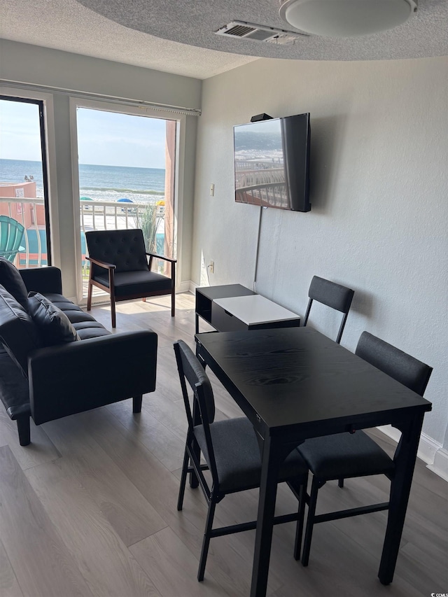 202 70th Ave N Unit 104, Myrtle Beach, SC 29572 - dining area featuring healthy amount of natural light, light wood-style flooring, a textured ceiling, a textured wall, and baseboards