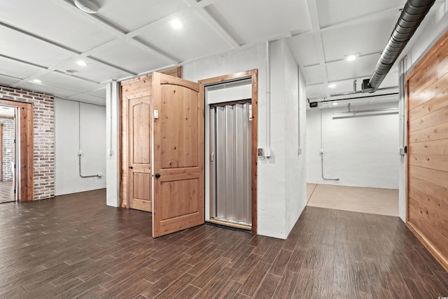 basement featuring dark hardwood / wood-style floors and brick wall