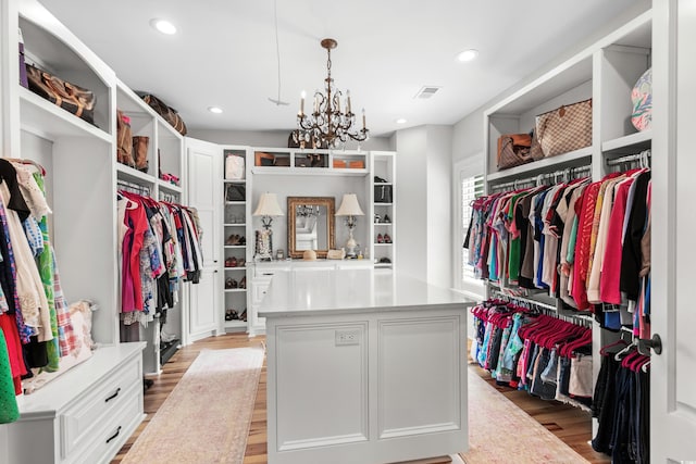 walk in closet with light wood-type flooring and a notable chandelier