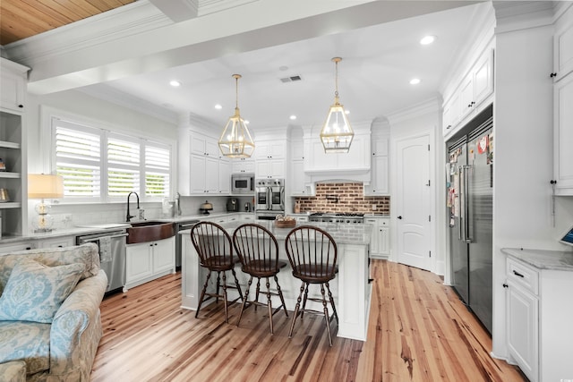 kitchen featuring pendant lighting, a kitchen island, light hardwood / wood-style flooring, white cabinets, and built in appliances