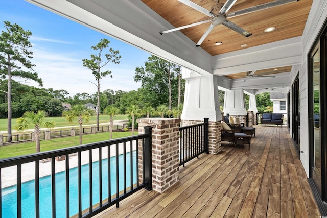 wooden deck featuring a fenced in pool, a lawn, and ceiling fan