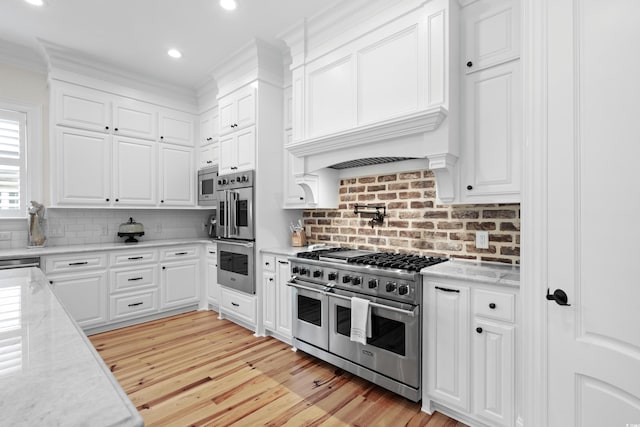 kitchen with stainless steel appliances, tasteful backsplash, light hardwood / wood-style floors, crown molding, and white cabinetry