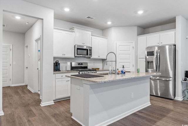 kitchen with dark wood-type flooring, an island with sink, stainless steel appliances, and white cabinetry